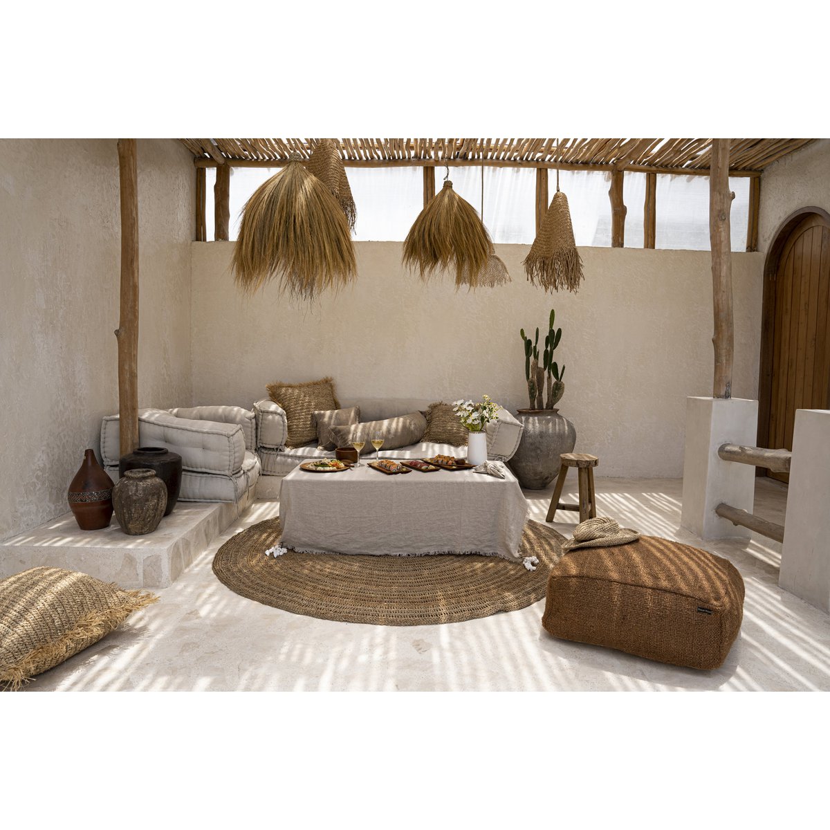Linnen tafelkleed beige 150x150 cm in een boho ruimte met rotan en raffia poefs en kleden