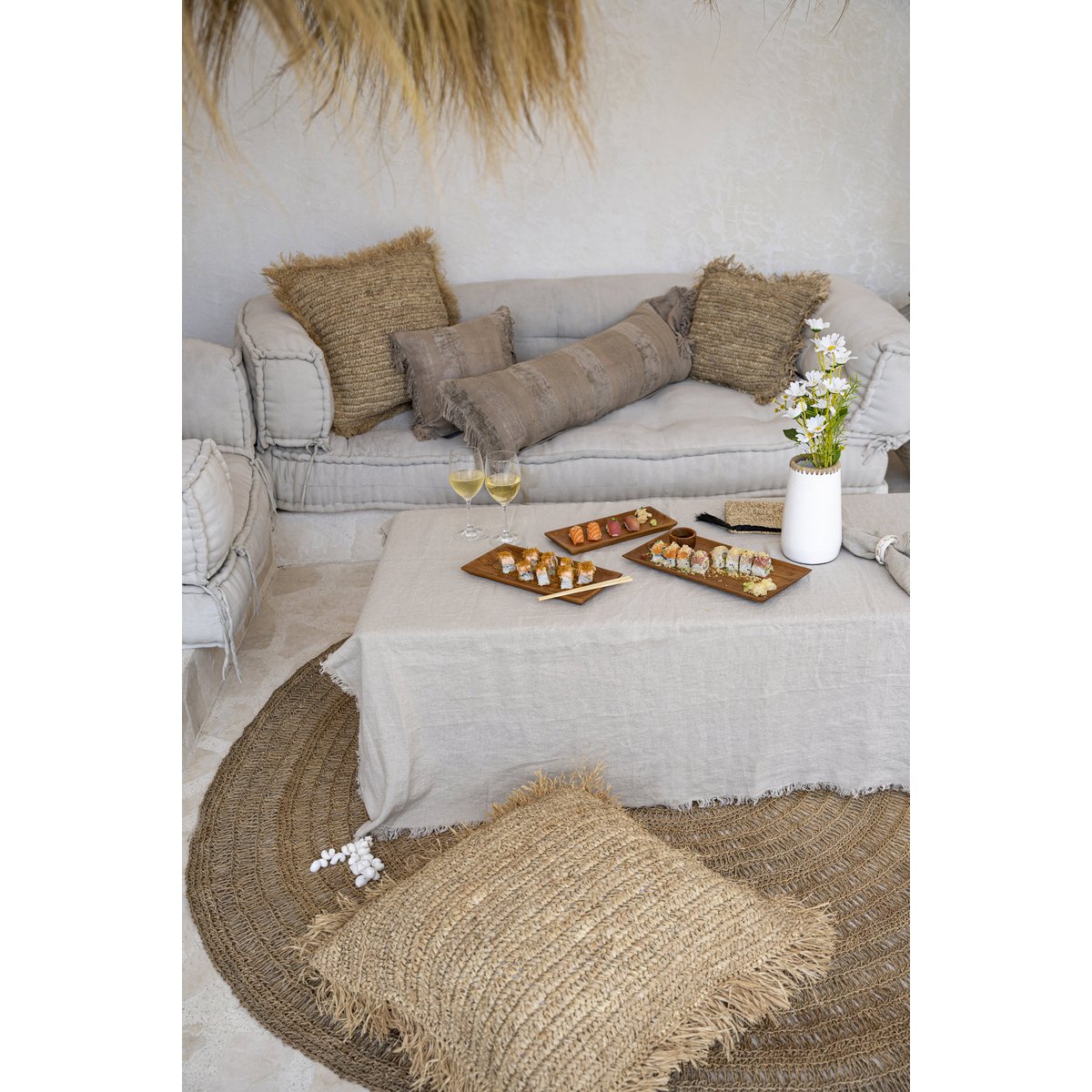 Linnen tafelkleed beige 150x150 cm in een boho ruimte met rotan en raffia poefs en kleden, en borrelplanken en glazen