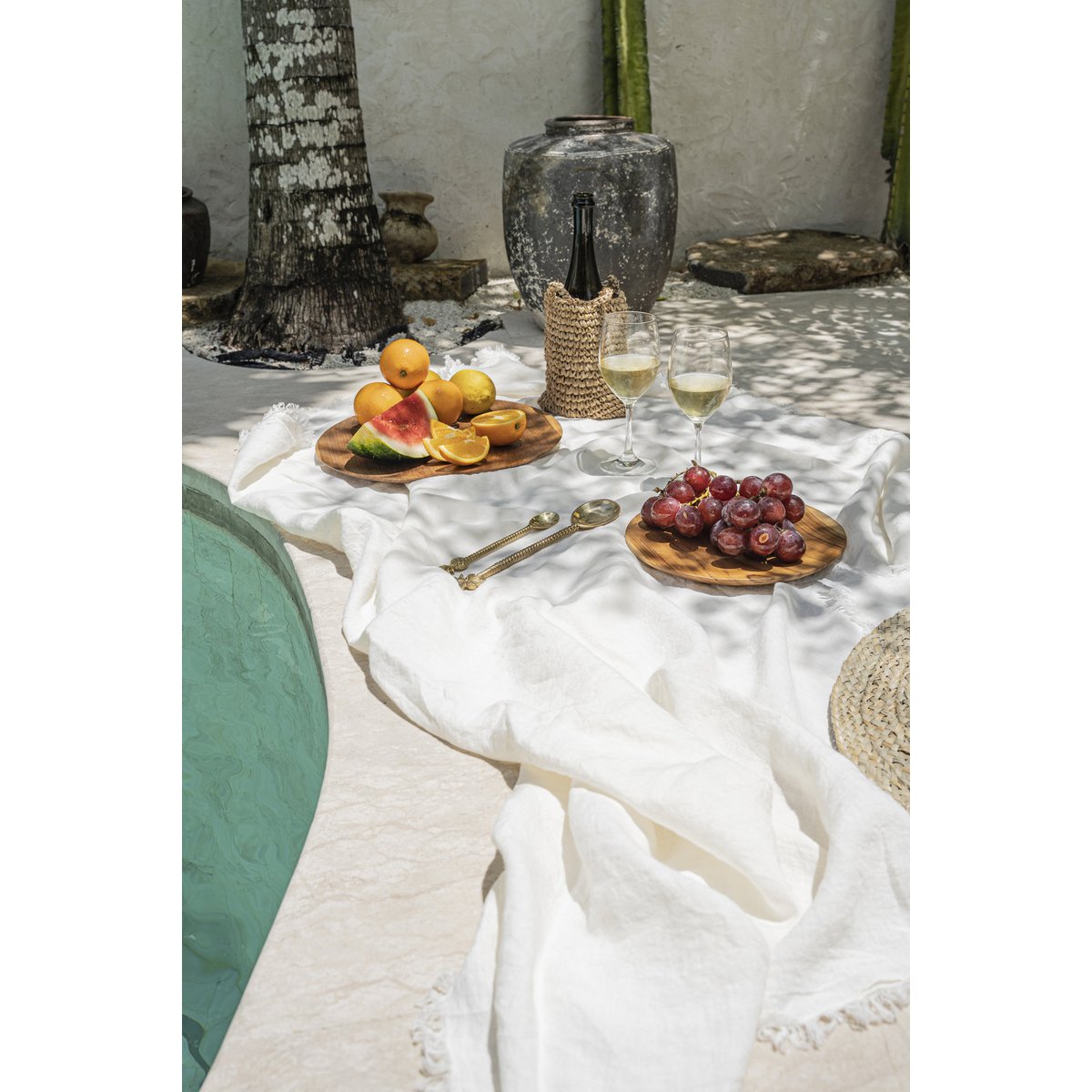 Linnen tafelkleed wit 150x150 cm buiten bij een zwembad met borrelplanken met fruit en drankjes