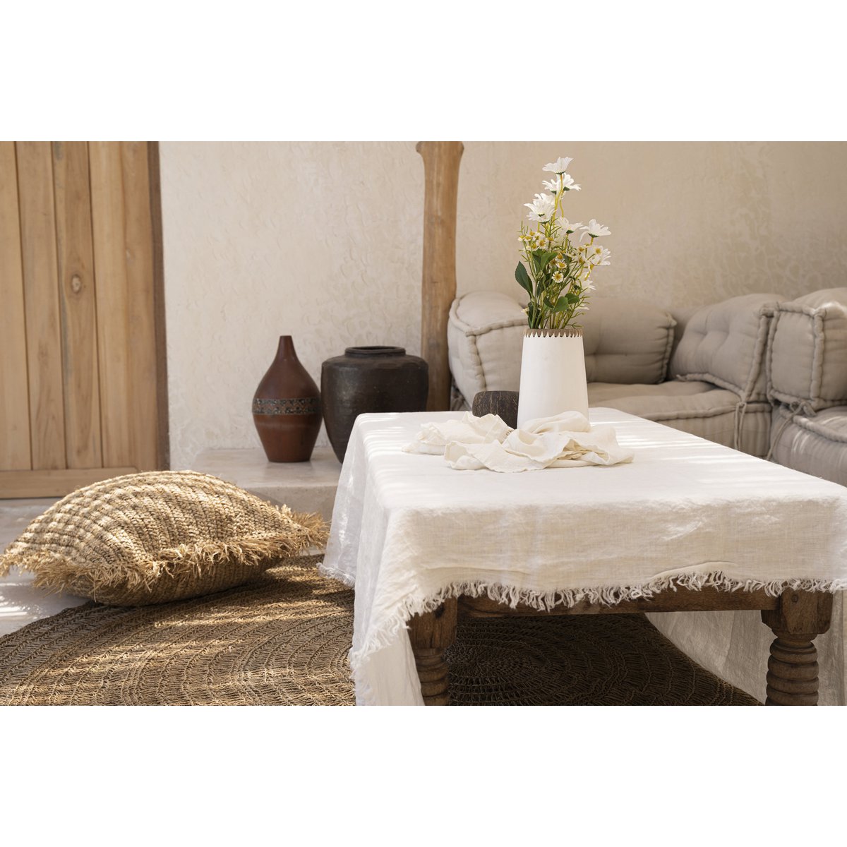 Linnen tafelkleed wit 150x150 cm op een terras op een bijzettafel met een witte vaas met planten erin
