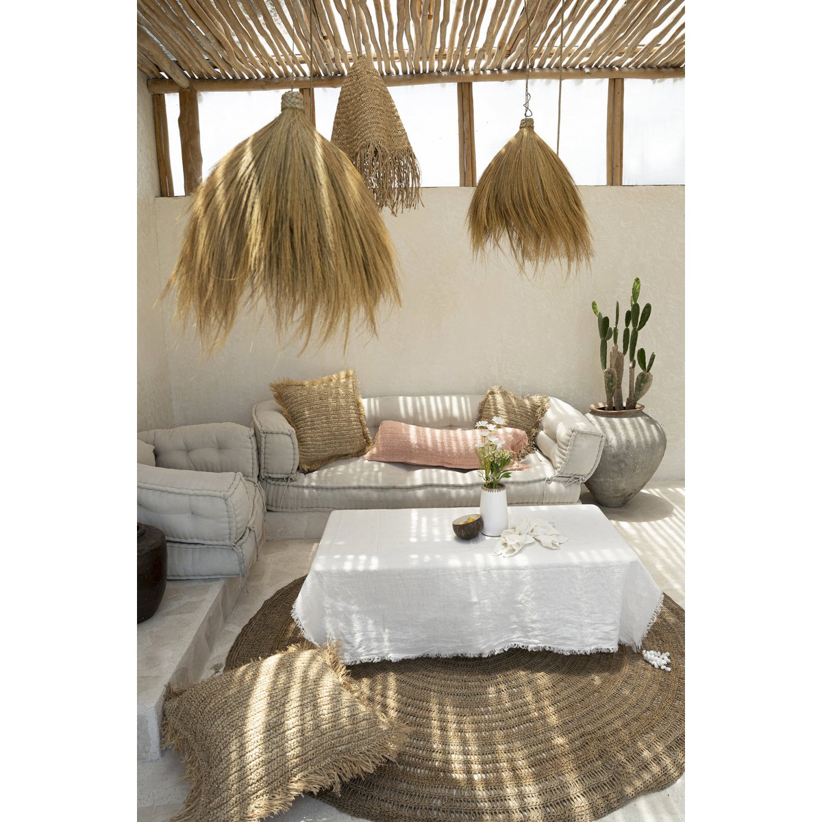 Linnen tafelkleed wit 150x250 cm opgevouwen buiten op een veranda over een bijzettafel met decoratie en vazen erop