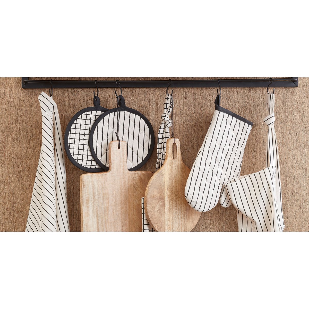 Serveerplank hangend aan een wandrek met keukenaccessoires.