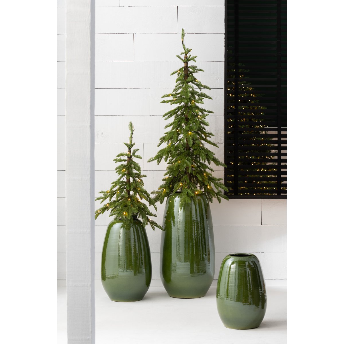Meerdere porseleinen groene vazen in verschillend formaat sfeerfvol gestyled in een modern interieur met planten en lampjes