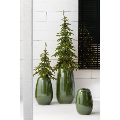 Meerdere porseleinen groene vazen in verschillend formaat sfeerfvol gestyled in een modern interieur met planten en lampjes