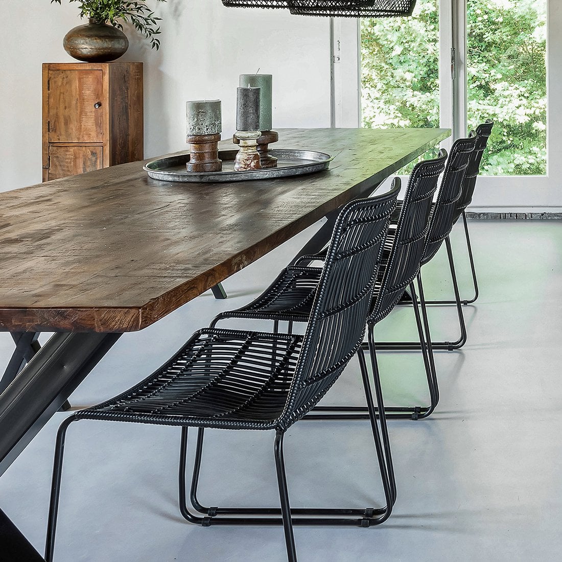 Meerdere zwarte rotan Jane stoelen aan een lange houten eettafel