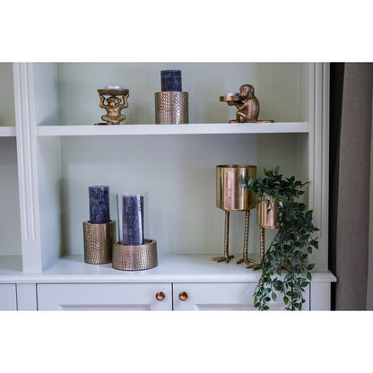 Gouden windlicht met glas op witte kast – stijlvolle woonaccessoire voor een modern interieur.

