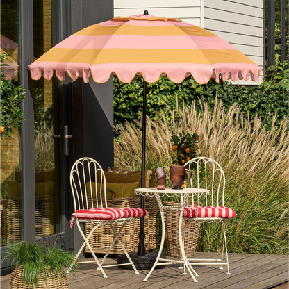 Parasol gestreept geel roze 238 cm op een terras met een wit bistro tuinsetje
