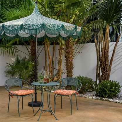 Parasol groen met franjes 235 cm buiten in een tuin boven een groen bistro tuinset, een waterkan en twee glazen op het tafeltje