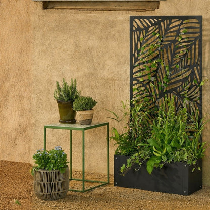 Plantenbak met klimrek zwart metaal 118 cm Sapri, in knusse tuin omringt door andere buitenpotten met groene planten 