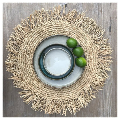Raffia placemat rond naturel 45 cm buiten op een houten tafel, met daarop een paar borden en schalen met fruit