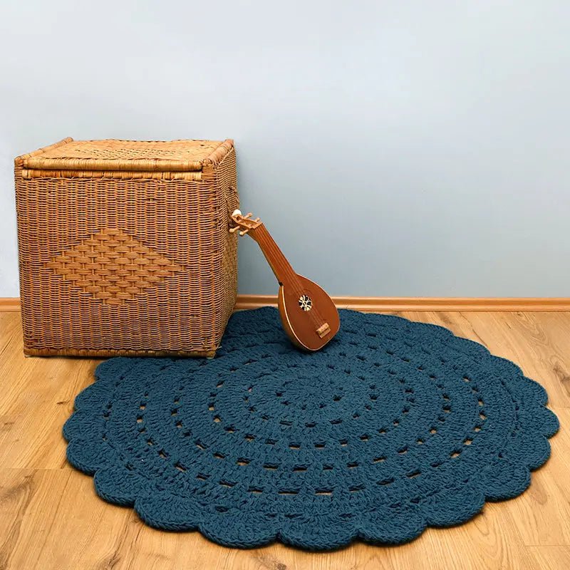 Rond vloerkleed blauw Alma van katoen naast een instrument en een rotan mand