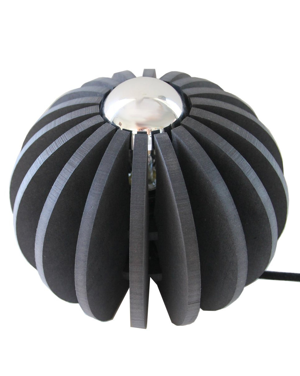 Deze compacte zwarte tafellamp valt op door zijn moderne, sculpturale ontwerp. De ronde vorm met open lijnen zorgt voor een stoere, eigentijdse uitstraling.
