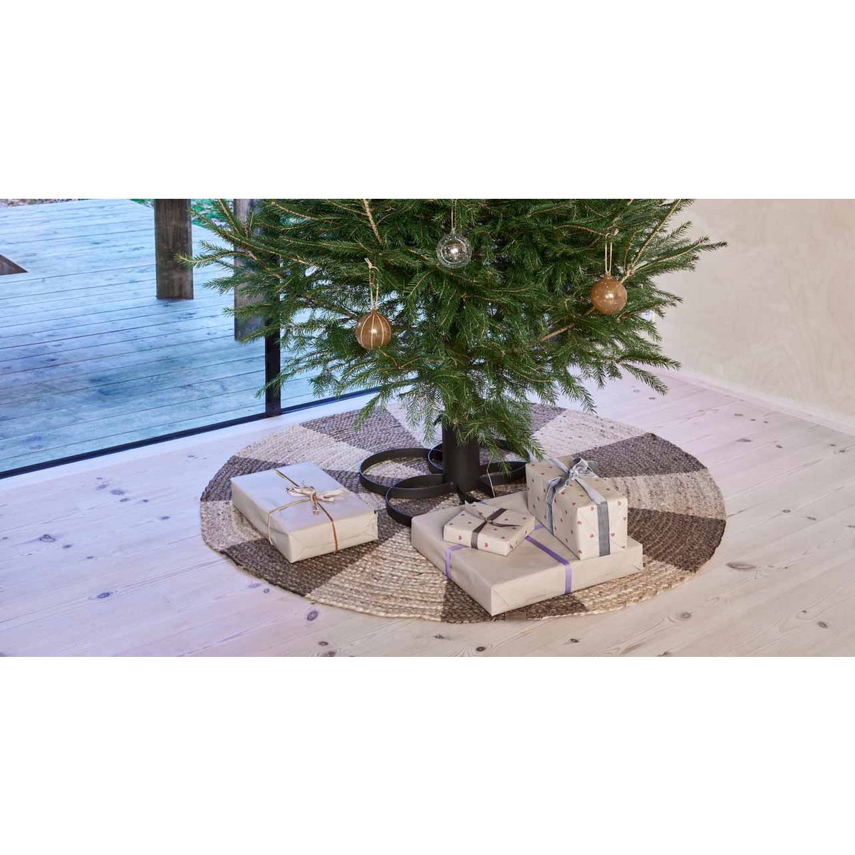 Zwarte kerstboomstandaard van metaal met geschenken eronder – sfeervol kersttafereel op houten vloer.