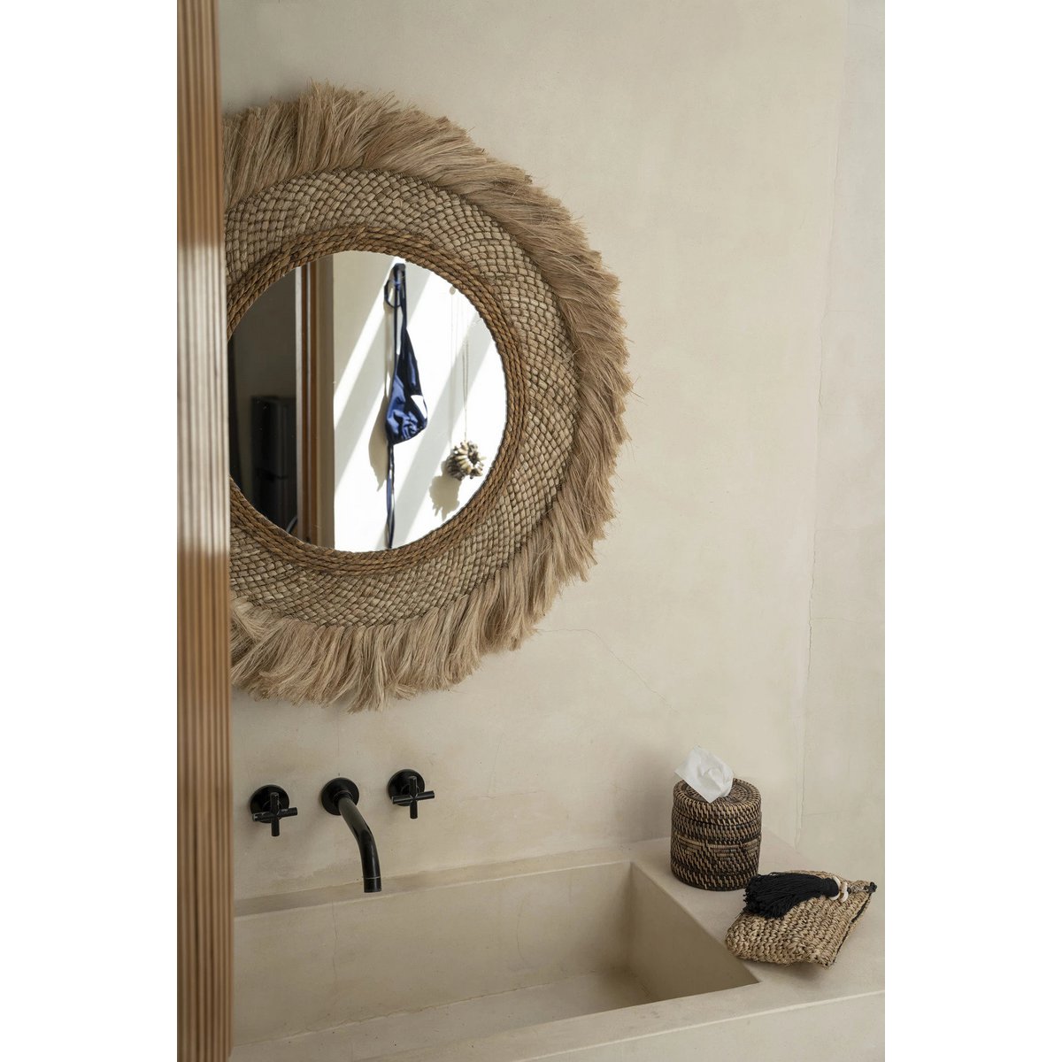 Rotan tissuehouder naturel rond met deksel in een boho badkamer met tissues erin, als detail naast een spiegel