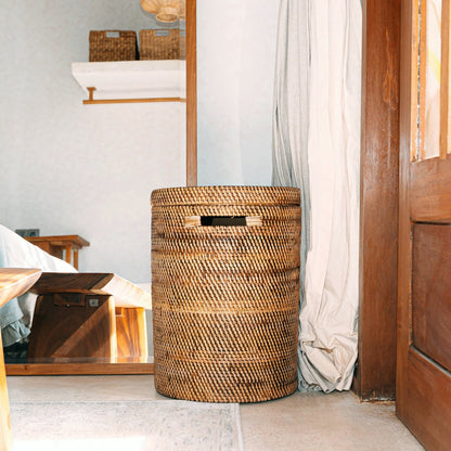 Rotan wasmand met deksel naturel Sari in een boho hal met spiegel, witte gordijnen en een houten kruk