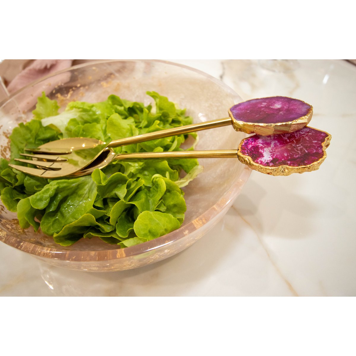 Saladebestek goud met roze agaat in een doorzichtige marmeren saladebak met sla erin