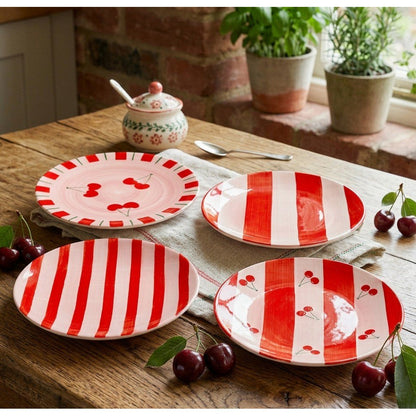 Set van 4 rode dessertbordjes met rood gestreepte patroon en afbeeldingen van kersjes erop op houten eettafel met kersen en servetten erop