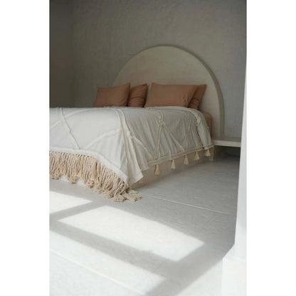 Beige katoenen plaid met decoratieve franjes op een bed in een lichte, serene slaapkamer met natuurlijke tinten. Een elegant en zacht woonaccessoire dat warmte en textuur toevoegt aan een bohemian of mediterraans interieur.