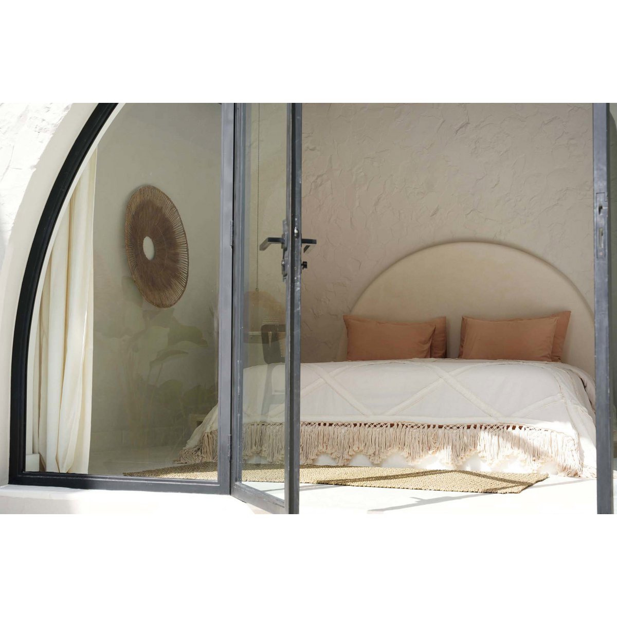 Beige katoenen plaid met decoratieve franjes op een bed in een lichte, serene slaapkamer met natuurlijke tinten. Een elegant en zacht woonaccessoire dat warmte en textuur toevoegt aan een bohemian of mediterraans interieur.