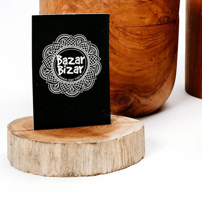 Teakhouten kaarthouder gebruikt als display voor een zwart kaartje op een houten ondergrond.