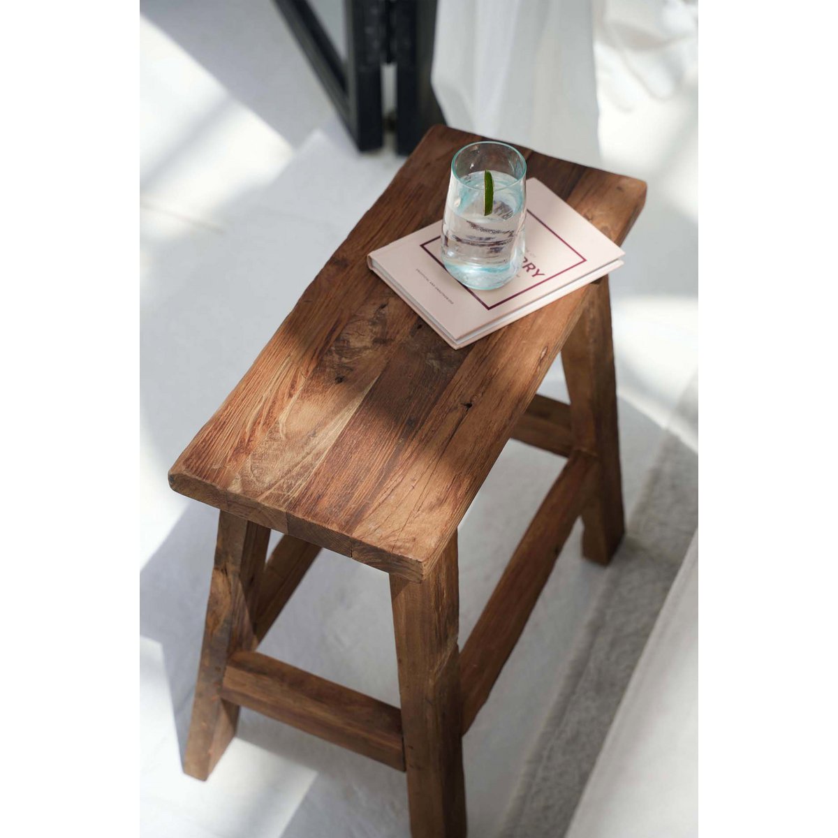 Teakhouten kruk kruk in moderne setting, gebruikt als bijzettafel