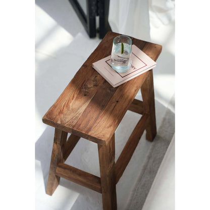 Teakhouten kruk kruk in moderne setting, gebruikt als bijzettafel