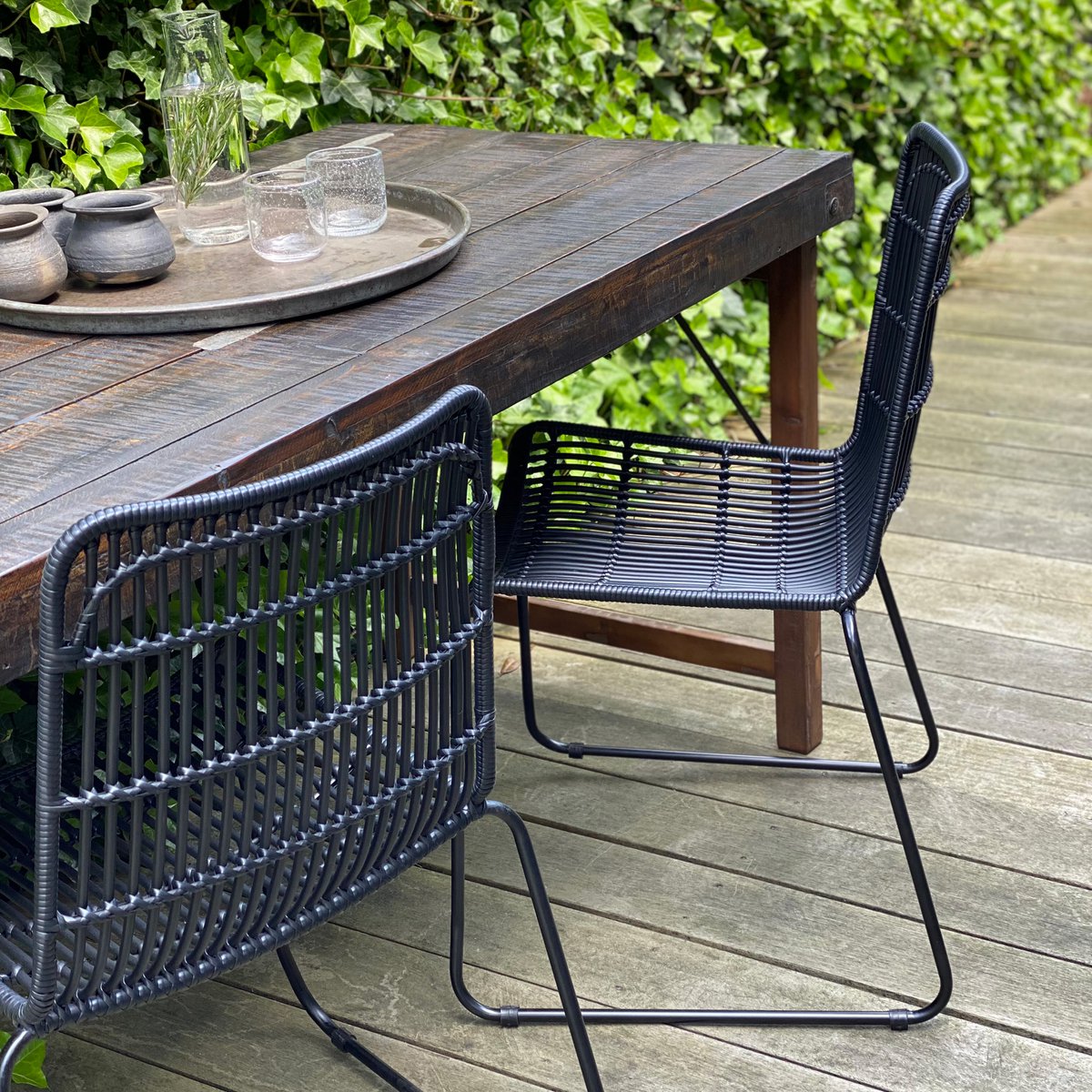 Tuinstoel rotan zwart Jane op houten terras aan houten tafel met een andere zwarte stoel