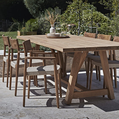 Tuinstoel teak donker met armleuning Freya in tuin aan grote tafel en meerdere stoelen