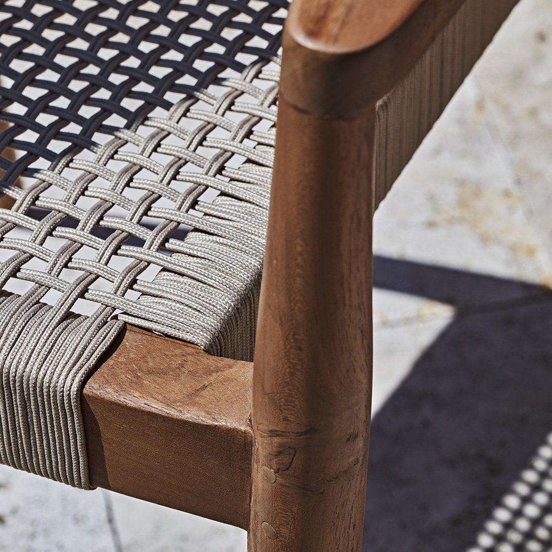 Tuinstoel teak donker met armleuning detail van de gevlochten zitting