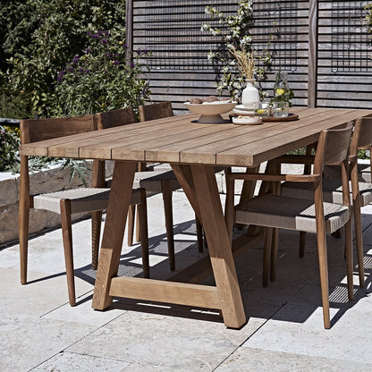 Tuinstoel teak donker naturel Freya met andere stoelen aan teakhouten tafel met decoratie