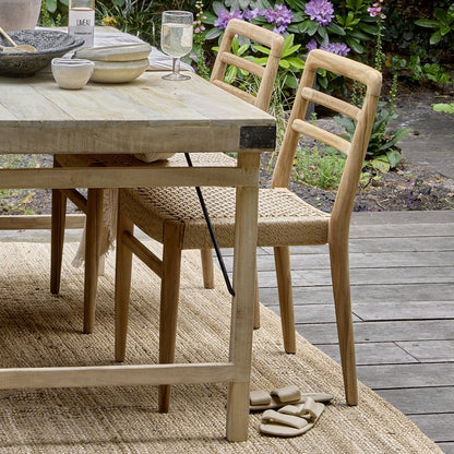 Tuinstoel teak in naturel Verano zonder armleuning in een tuin jute kleed bij gedekte tafel