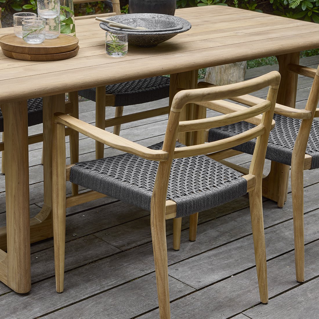 Tuinstoel teak zwart met armleuning Verano aan een houten tafel met andere Verano tuinstoelen