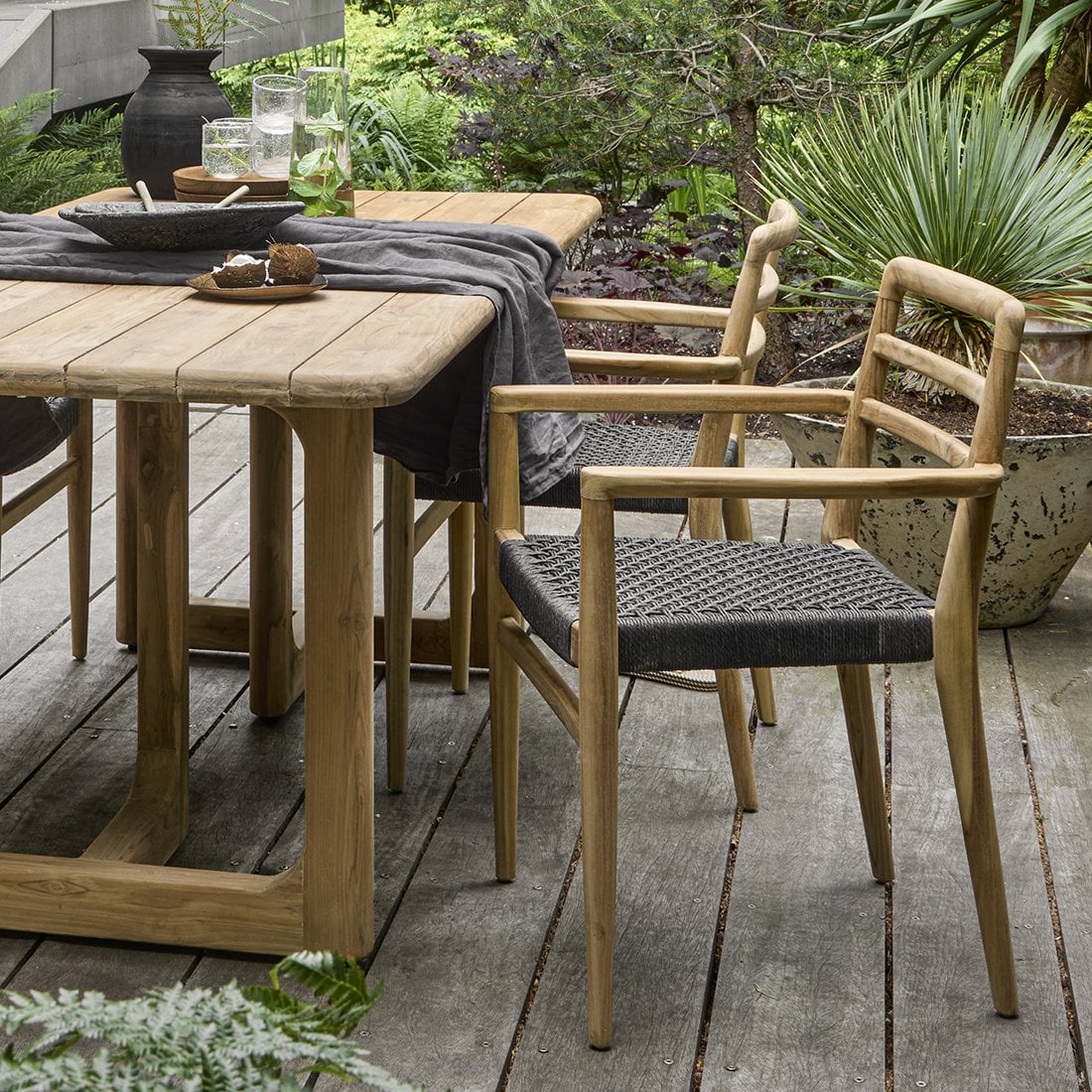 Tuinstoel teak zwart met armleuning Verano aan houten bijzettafel in een gezellige knusse tuin