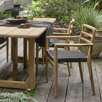Tuinstoel teak zwart met armleuning Verano aan houten bijzettafel in een gezellige knusse tuin
