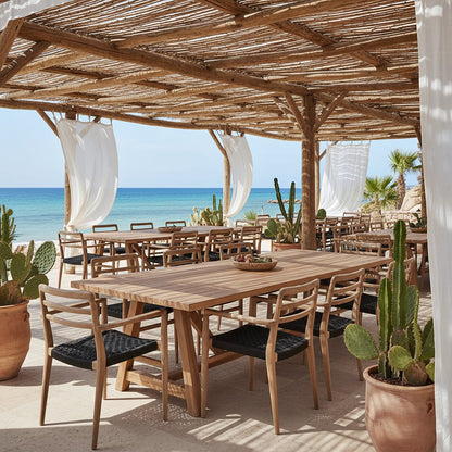 Tuinstoel teak zwart met armleuning Verano buiten op een overdekt terras met meerdere andere tafels en stoelen aan het strand