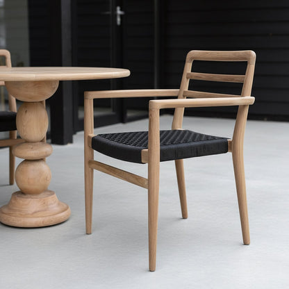 Tuinstoel teak zwart met armleuning Verano op veranda met op de achtergrond een organische houten tafel