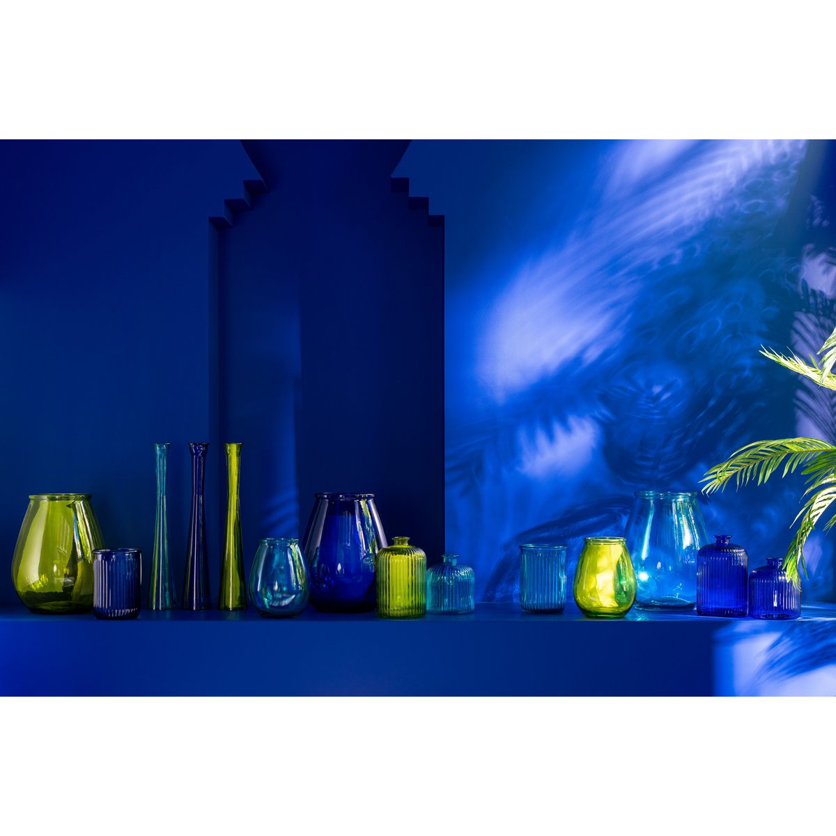 Verschillende vormen en kleuren glazen vazen sfeervol gestyled op een blauw achtergrond