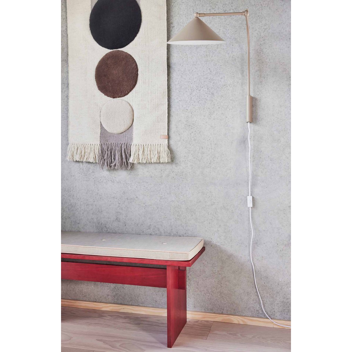 Wandlamp wit Kasa met verstelbare arm tegen grijze muur aan naast muurtapijt en rood krukje