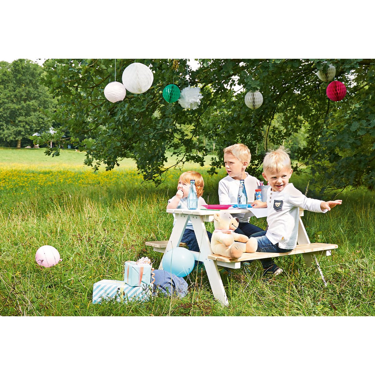 Kinderen zitten en hebben plezier op het witte houten picknickbankje Nicki