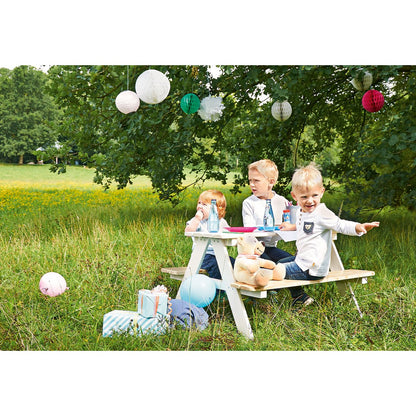 Kinderen zitten en hebben plezier op het witte houten picknickbankje Nicki