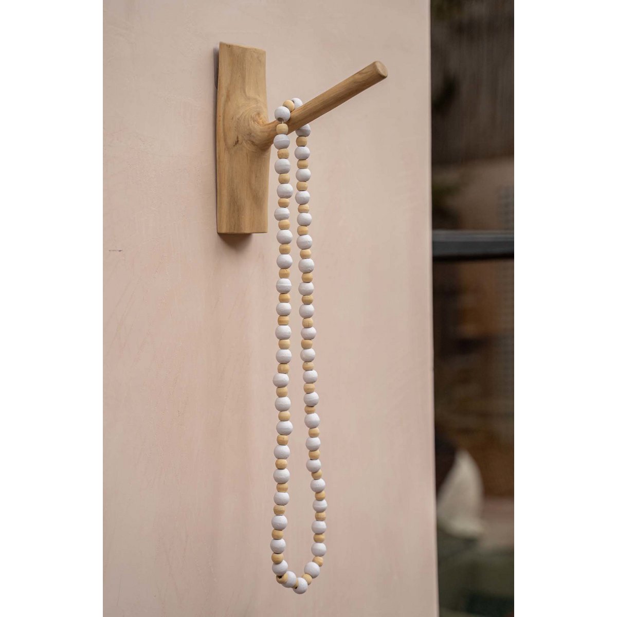 Lange houten kralenketting Canggu hangend aan wand