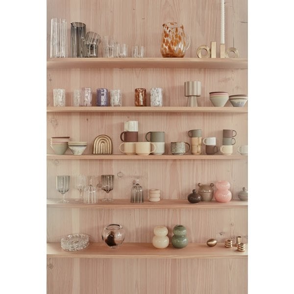 Mix van keramieken mokken, glazen en kommen op houten planken – Scandinavisch interieur met designservies.