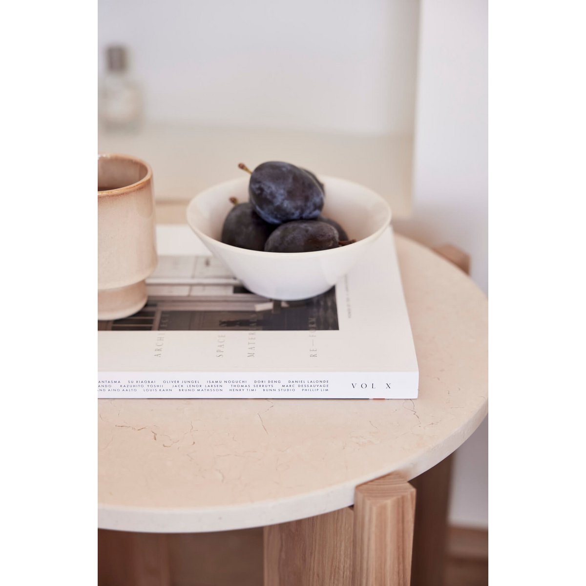 Witte keramieken kom met pruimen op salontafel – minimalistisch servies in Scandinavisch interieur.