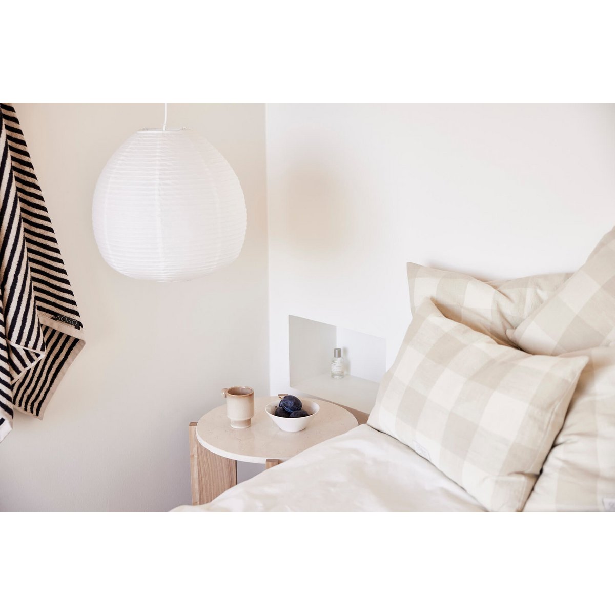 Witte keramieken kom en beige mok op nachtkastje – natuurlijke slaapkamerstyling met minimalistische accessoires.