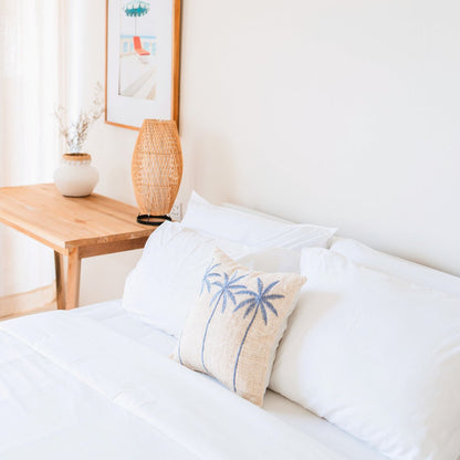 Witte kussenhoes met blauw palmmotief Anarka gestyled in een boho slaapkamer