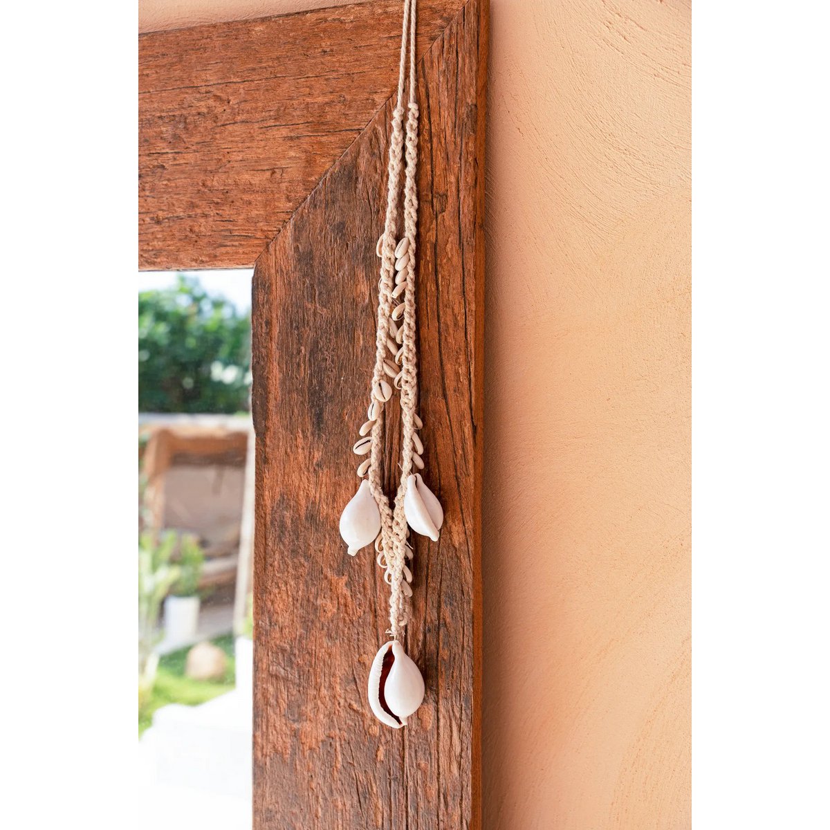 Witte cowrie schelpketting hangend aan houten ladder in interieur
