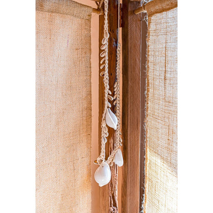 Cowrie schelpketting gedrapeerd over houten plank