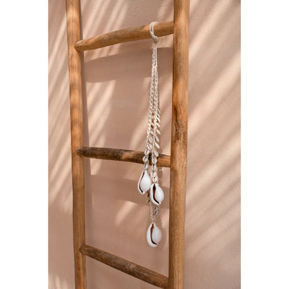 Bohemian schelpketting met witte cowrie schelpen aan wand