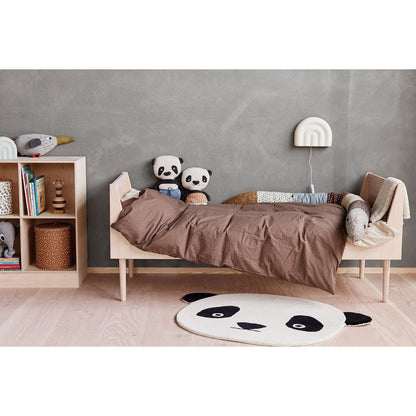 Witte siliconen wandlamp boven een bed in een sfeervolle kinderkamer