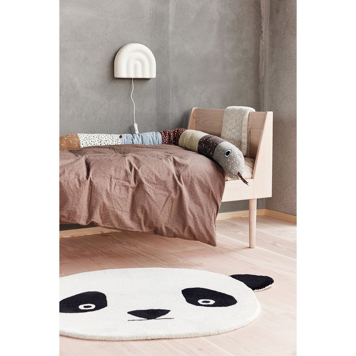 Witte siliconen wandlamp boven een bed in een sfeervolle kinderkamer